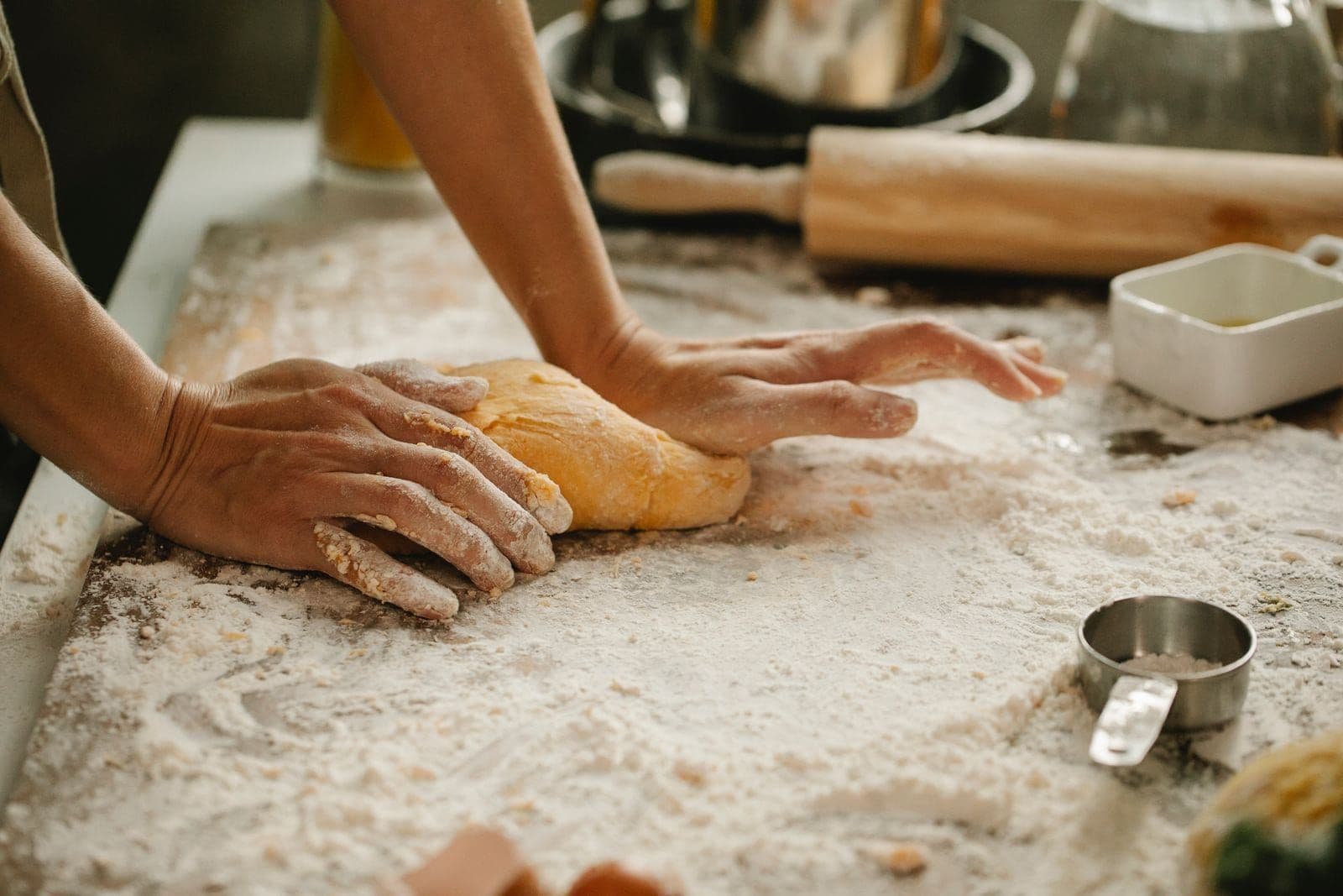Hands kneading dough on a flour-dusted worktop